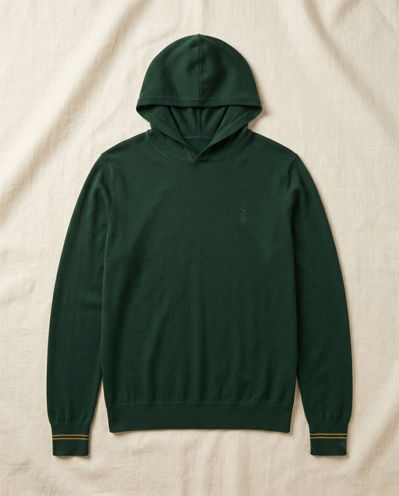 A thin solid racing-green knit hoodie with no drawcords and twin gold lines at each cuff, laid flat on cream linen.